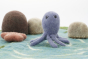 Close up of the Papoose purple octopus figure on a blue play mat in front of some Papoose rocks