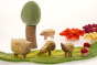 Close up of the Papoose childrens wooden pebble animal toys on a green play mat in front of a Papoose tree