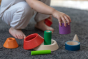 Child playing with the the Plan Toys Coloured Sorting Cones - a fun sorting game for toddlers, made up of 8 colourful hollow wooden cone and cylinder shapes that nest within each other.