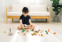 Young girl sat on the floor playing with the PlanToys stacking wooden countryside blocks