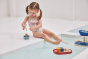 Girl sat on the edge of a swimming pool playing with the PlanToys wooden walrus sailing boat water toy