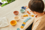Close up of child playing with the PlanToys plastic-free Waldorf cups and counters set on a table