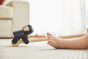 Close up of the PlanToys wooden gorilla pull along toy on a white carpet next to a child's feet
