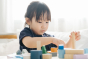 Close up of a young girl playing with the PlanToys plastic-free urban city blocks on a white table