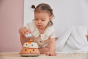 Girl leaning over to place a toy egg on top of the PlanToys stacking wooden bowls