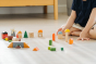 Close up of a childs hands playing with the PlanToys solid wood stacking countryside blocks on a white floor