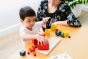 Child and woman sat at a table playing with the PlanToys wooden nesting and matching shapes set