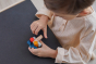 Close up of young child slotting together pieces from the PlanToys wooden logs puzzle on a black table