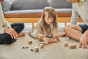 Young girl laying on the floor playing with the small wooden dog figure from the PlanToys plastic-free storytelling dice set