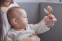 Close up of mother and baby holding the PlanToys wooden Shake N Clap baby rattle toy