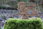 Reel wood handmade dinosaur toys stacked on a mossy tree stump