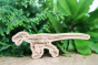 Reel wood eco-friendly wooden velociraptor toy in front of a green plant