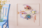 Studio Roof DIY craft fish wall decorations on a light pink wall next to a blue chair and glass vase