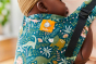 Close up of a baby inside a Tula dark green dinosaur print baby carrier