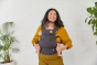 Woman stood holding a baby inside a Tula explore front facing baby carrier in the dark grey colour
