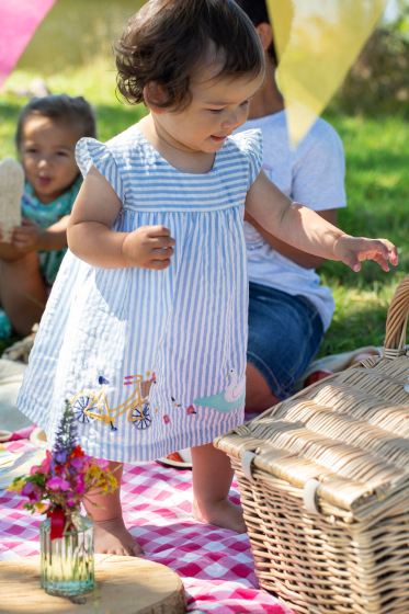 Child wearing the Frugi  Beach Hut Blue Stripe Birdie Body Dress showing the front of the dress