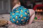 Baba + Boo Toucans Nappy worn by baby with toys on the floor
