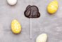 Cocoa Loco fairtrade dark chocolate easter bunny lolly on a grey background next to some yellow and white easter eggs