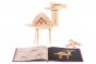 Kapla beginner art book open in front of a wooden camel model on a white background