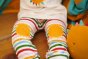 Close up of a child wearing the Little Green Radicals organic cotton sunshine knee patch rainbow stripe joggers