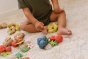 Close up of the oli and carol fruit and nut natural rubber baby teething toys laid out on a carpet in front of a childs feet