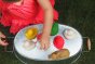 Close up of a child playing with the oli and carol natural rubber bath toys in a metal basin