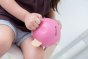 Close up of a girl holding the Plan Toys childrens pink eco-friendly wooden piggy bank 
