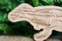 Close up of the reel wood eco-friendly wooden trex toy in front of a green plant
