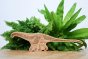 Reel wood handmade brontosaurus dinosaur toy in front of some green plants