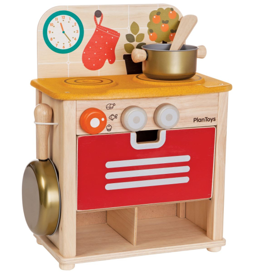 The PlanToys Wooden Play Kitchen Set. with a colourful splashback, red oven door, yellow hob and three turning knobs. White background.