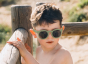 Young boy stood next to a wooden fence wearing the bird eyewear flexible kids sunglasses