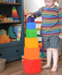A child stacking the boxes from the Grimm's Large Coloured Boxes Set on top of each other