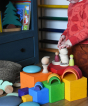 The blocks from the Grimm's Large Coloured Boxes Set placed in the floor with pieces of a Grimm's mini rainbow placed on top of them along with other wooden toys. An additional yellow box can be seen at the front 