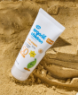 A bottle of the Green People Organic Lavender Children Sun Cream SPF50 100ml, propped up by a sandcastle