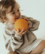 Toddler holding the Oli & Carol 100% Natural Rubber Baby Sensory Ball - Orange
