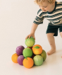 Toddler stacking a variety of Oli & Carol 100% Natural Rubber Baby Sensory Balls