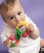 Baby chewing on Oli & Carol Natural Rubber Baby Teething Ring - Fruit with a purple background