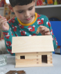 A child patiently and carefully building a WALACHIA hobby kit, and adding a glued block to the top of the roof