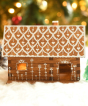 A beautifully festive decorated WALACHIA log cabin house. There are little fairy lights in the house creating a lovely warm glow inside, white painted roof tiles and white painted dots and hears decorated around the windows
