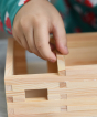 A close up of the wooden sticks being glued and put together to creating an amazing WALACHIA building. A child is carefully adding the wooden stick to the building