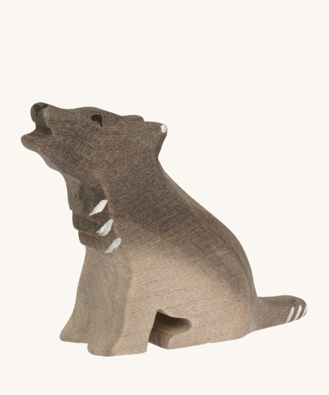 Bumbu wooden sitting wolf, hand crafted and hand painted with white painted details, on a cream background