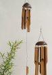 Two Bamboo Windchimes with Coconut Top hung up with a plant seen in the background