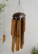 Bamboo Windchime with Coconut Top hung up with a plant seen in the background