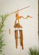 Namaste Bamboo Windchime with Nodding Bird decoration pictured hanging up with plants in the background 