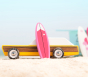One of the three surfboards leaning against a vintage toy car.