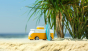 Close up of a Candylab sunset beach van toy on a sandy beach in front of some palm trees