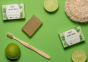 Bio-D natural Vegan aloe vera and lime soap bar on a green background surrounded by limes and a bamboo toothbrush 