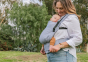 Close up of woman stood in a park with a baby in a Tula light blue FTG baby carrier
