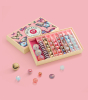 Billes & Co Butterfly Anamorphic Glass Marbles Set box, with various pink, blue, yellow and frosted marbles inside and in front of their box, on a pink background