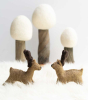 2 Papoose handmade felt reindeer toy figures stood on a white fluffy blanket in front of 3 Papoose winter trees